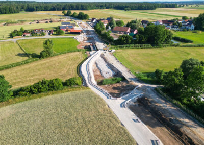 Luftaufnahme einer neuen Straße zum Dorf inmitten von Feldern bei Reckenstetten.